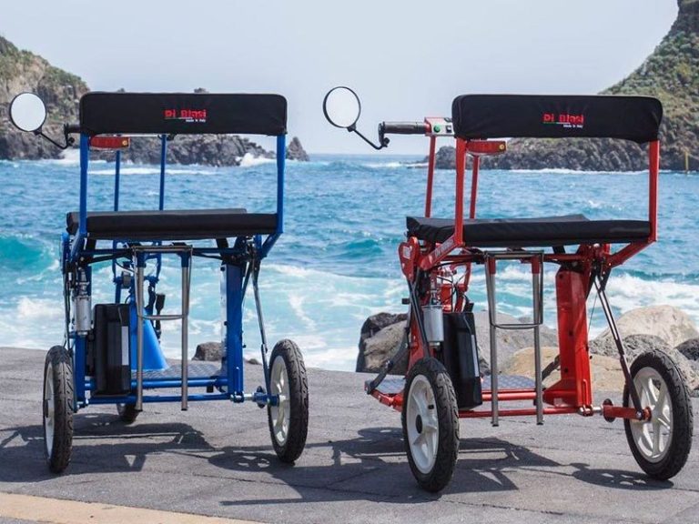 Zwei DiBlasi R30 Elektroscooter stehen auf einer Strandpromenade.